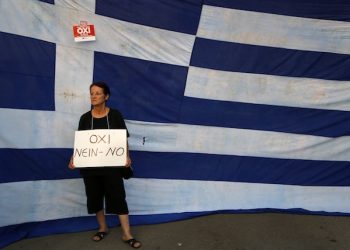 A supporter of a NO vote in the upcoming referendum, holds a placard reads ''NO'' during a rally at Syntagma square in Athens Monday, June 29, 2015. Anxious Greek pensioners swarmed closed bank branches and long lines snaked at ATMs as Greeks endured the first day of serious controls on their daily economic lives ahead of a July 5 referendum that could determine whether the country has to ditch the euro currency and return to the drachma. (AP Photo/Petros Karadjias)
