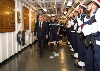 This photo released on Friday, Dec. 4, 2015 by the French Army Communications Audiovisual office (ECPAD) shows France's President, Francois Hollande, left, reviewing an honor guard upon his arrival aboard the Charles De Gaulle aircraft carrier operating off Syria in the Mediterranean sea. French President Francois Hollande is visiting the aircraft carrier launching airstrikes against the Islamic State group. The Charles de Gaulle has launched raids against Islamic State bases since the Nov. 13 attacks that killed 130 in Paris. (Christian Cavallo/ECPAD via AP)     THIS IMAGE MAY ONLY BE USED FOR 30 DAYS FROM TIME TRANSMISSION.