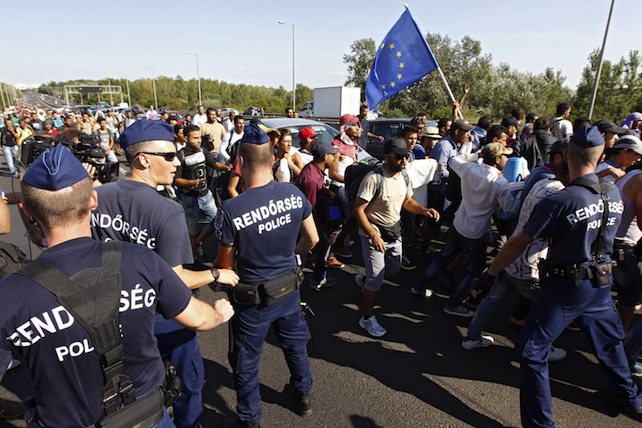 epa04912900 Police defines the way of the migrants walking - one with an EU flag - on the Budaorsi Street, in Budapest,  Migrants walk along Budaorsi Street on their way out of Budapest, Hungary, 04 September 2015. Several thousand migrants left the Keleti station this afternoon heading for Germany on foot. Hundreds of migrants on 03 September rushed the platforms in Budapest after Hungarian police opened the city's Keleti station, which had been blocked to migrants since 01 September. Hungary's railway service said there were no trains headed to Western Europe for the time being. Thousands of refugees - many of whom have traveled from Africa and the Middle East in the hopes of reaching countries like Germany and Sweden - have been stranded at the station.  EPA/ZSOLT SZIGETVARY HUNGARY OUT
