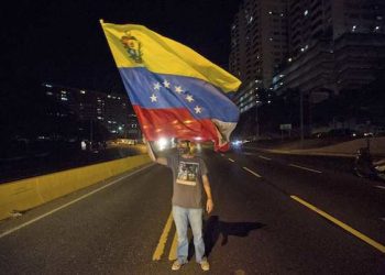 An opposition member waves a Venezuelan flag during a protest against Venezuela's President Nicolas Maduro in Caracas, Venezuela, Thursday, March 30, 2017. Venezuela's Supreme Court ruled it can take over the powers of congress in what opponents of President Maduro as well as foreign governments denounced as the latest step toward installing a dictatorship in this South American nation. (AP Photo/Fernando Llano)