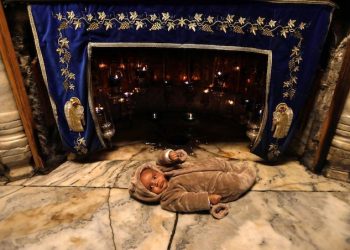 epa07215160 A visitor placed a baby at the Grotto inside the Church of the Nativity, built atop the site where Christians believe Jesus Christ was born, on Christmas Eve, in the West Bank city of Bethlehem, 07 December 2018. The Church of the Nativity, built on the site where Jesus Christ is believed to have been born in the West Bank city of Bethlehem, is administered jointly by Greek Orthodox, Roman Catholic, Armenian Apostolic and Syriac orthodox church.  EPA/ABED AL HASHLAMOUN