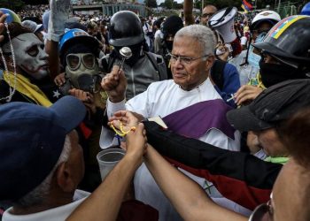 epa06048617 A priest blesses protesters during a demonstration called 'Venezuela gives a message to the Armed Force' in Caracas, Venezuela, 24 June 2017. The Venezuelan opposition marched to the military bases of the Capital while chavists commemorated the 196th anniversary of the Carabobo battle.  EPA/Miguel GutiÈrrez