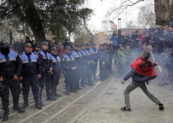 epa07415242 A protester throws a firecracker in front of unimpressed police during a protest outside the Albanian parliament in Tirana, Albania, 05 March 2019. Opposition MPs have resigned from their parliamentary mandates, and protesters demand the government's resignation and early elections.  EPA/MALTON DIBRA