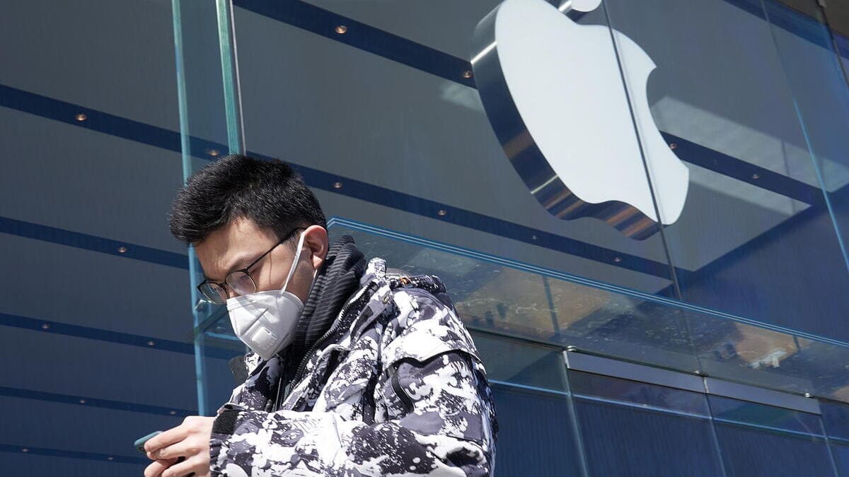 Un ragazzo cinese guarda l'iPhone mentre passa davanti a un negozio della Apple in Cina
