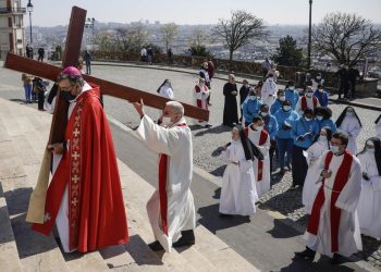 Il vescovo di Parigi, Michel Aupetit, porta la croce durante una Via Crucis nella capitale francese (foto Ansa)