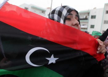 Una donna sventola la bandiera della Libia