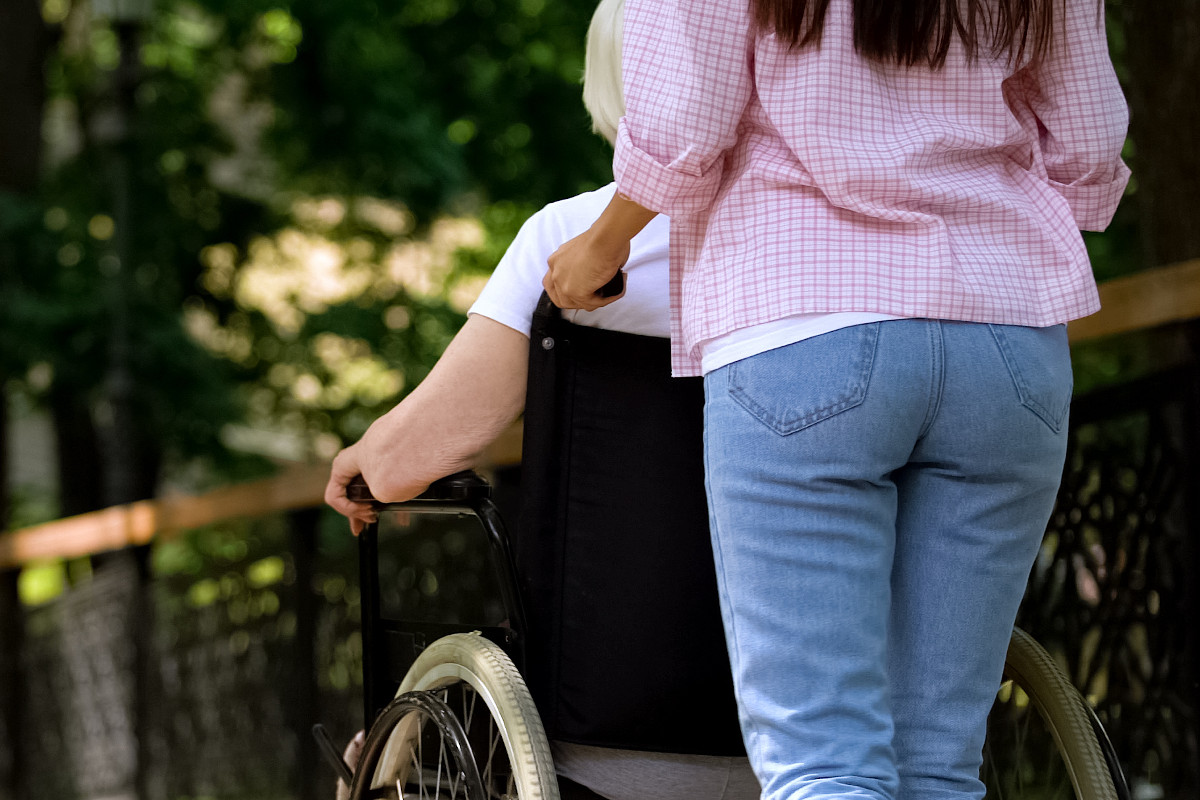 Ragazza spinge una donna anziana in sedia a rotelle