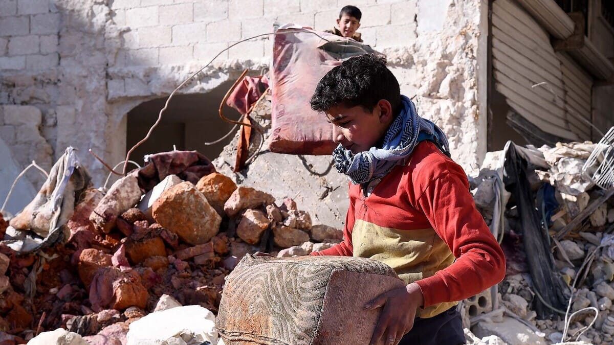 Un ragazzo ad Aleppo recupera alcuni oggetti personali dalle macerie del devastante terremoto che ha colpito la Siria