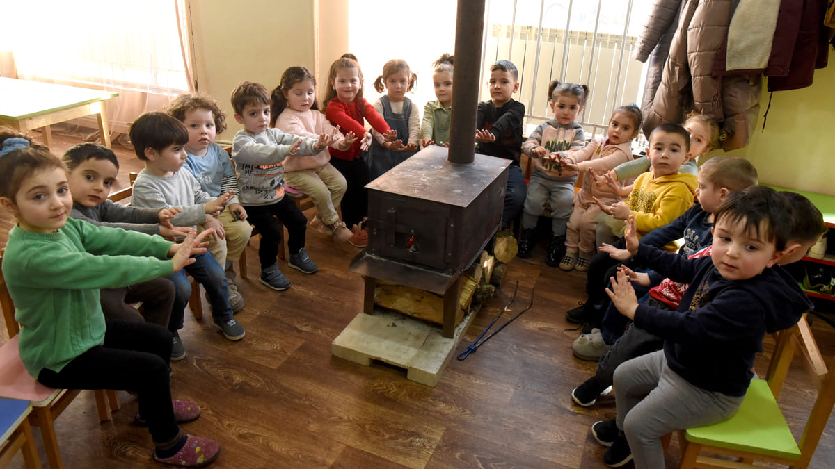 Bambini armeni in Artsakh si scaldano davanti a una stufa