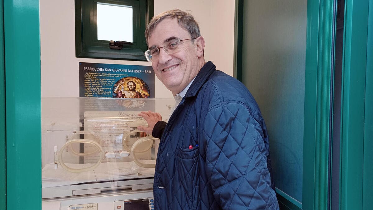 Don Antonio Ruccia di fronte alla culletta termica installata nel 2014 davanti alla parrocchia di San Giovanni Battista di Bari per le mamme in difficoltà (foto Ansa)
