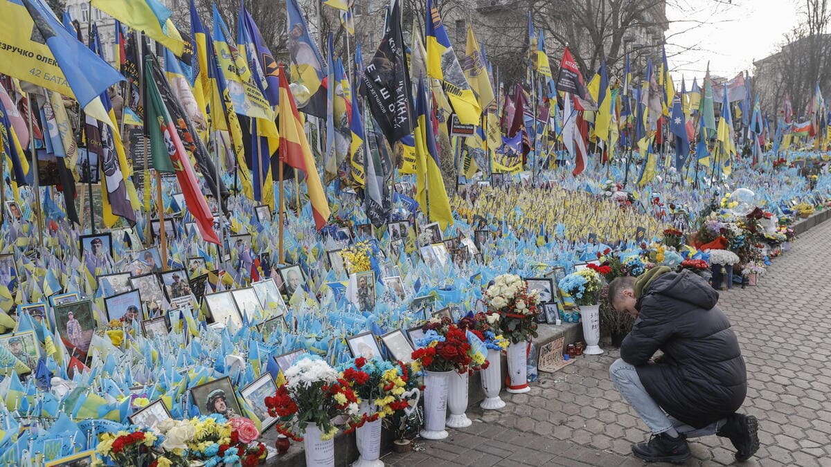 Un uomo si inginocchia davanti al memoriale dei caduti nella guerra tra Russia e Ucraina a Kiev
